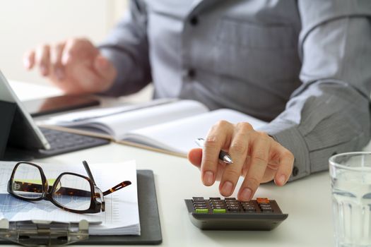 businessman hand working with finances about cost and calculator and latop with mobile phone on withe desk in modern office 