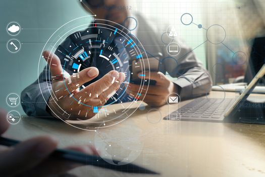 Hands of businessman using mobile phone in modern office with laptop and digital tablet computer in team meeting with VR icon diagram