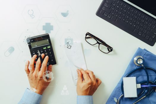 top view of Healthcare costs and fees concept.Hand of smart doctor used a calculator for medical costs in modern hospital with VR icon diagram