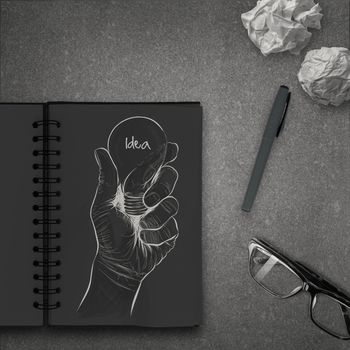 Hand drawn light bulb with IDEA word on dark note book as concept 