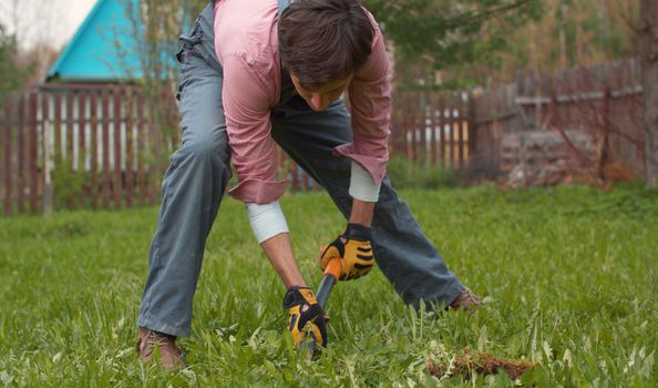 Gardener digging land on a lawn in the yard. Young handsome man with the shovel on the meadow. People, nature, farming concept