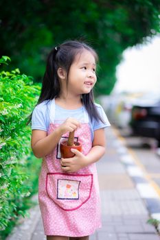 Portrait of little girl in apron with mortar in the park