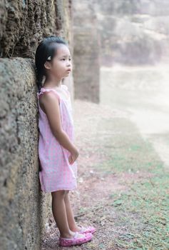 Little asian girl with dress standind on th rock of historic site in Thailand