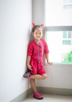 little girl in red dress standing and smile at home