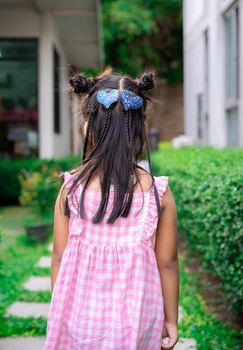 Back view of adorable little girl with beautiful hair walking in the park