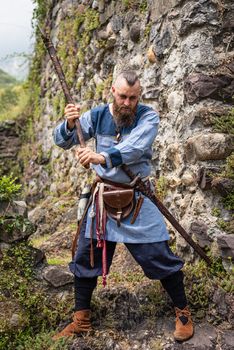 Viking warrior brandishes an ax in a threatening way, portrait in the shape of a man in medieval clothes