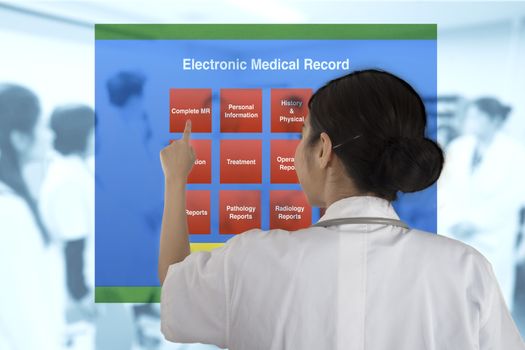 Female doctor pointing to choose working item from electronic medical record menu with blur background of doctor meeting.