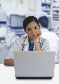 Female doctor working with laptop computer on desk in hospital.