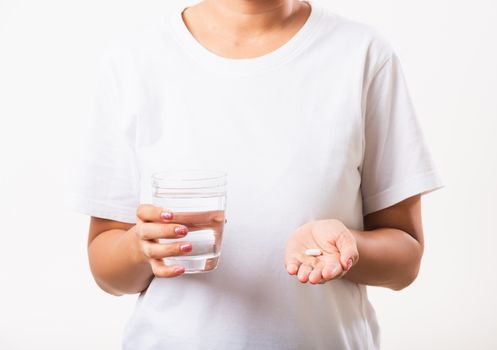 Closeup young Asian woman hold pill drugs in hand ready take medicines with a glass of water, studio shot isolated on white background, Healthcare and medical pharmacy concept