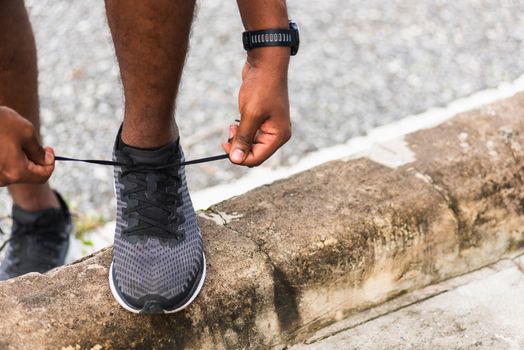 Close up Asian sport runner black man wear watch stand step on the footpath trying shoelace running shoes getting ready for jogging and run outdoor street health park, healthy exercise workout concept