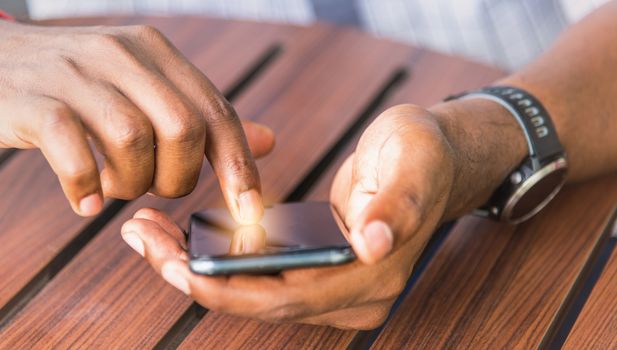 Happy Asian hand black man person holding a modern smart phone and touching a finger to blank screen device technology and connecting networking online at the coffee cafe shop