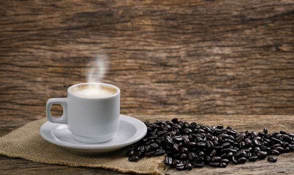 Coffee cup and coffee beans roasted in a sack on a wooden floor.