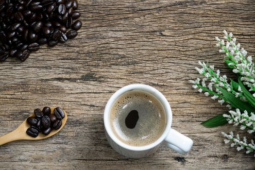 Coffee cup and coffee beans roasted in a sack on a wooden floor.