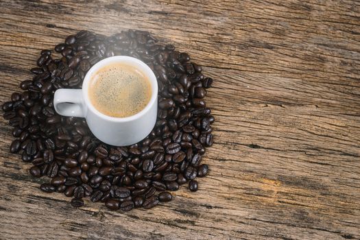 Coffee cup and coffee beans roasted in a sack on a wooden floor.