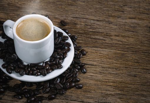 Coffee cup and coffee beans roasted in a sack on a wooden floor.