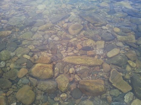 Transparent water surface with copy space for background and texture. Transparent water texture with view of stones under water.