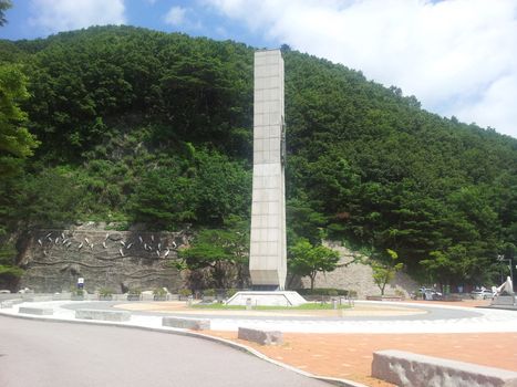 Monument minerate of soyang dame with green mountains and bluse sky in the background. This monumet is in Chuncheon city of South Korea.