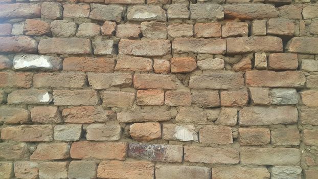 Closeup texture of red brick wall. A background of a weathered old exterior brick wall in the sunshine.