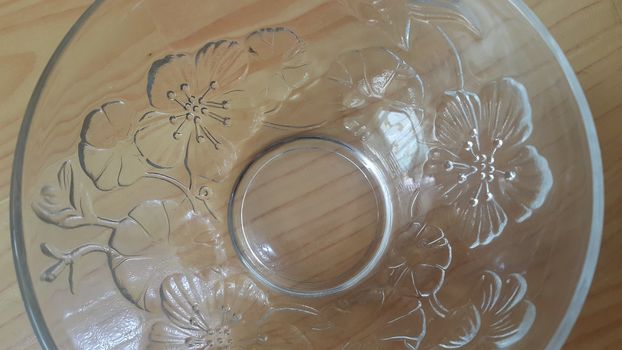 Top view of empty white glass bowls on a wooden floor. Glass bowl with flowers made on its wall