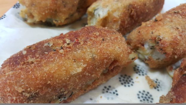 Closeup perspective view of home made spicy and delicious croquettes served in ceramic plate over wooden floor