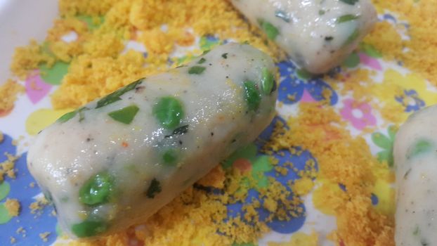 Closeup perspective view of home made uncooked spicy and delicious croquettes placed with bread crumb in ceramic plate.