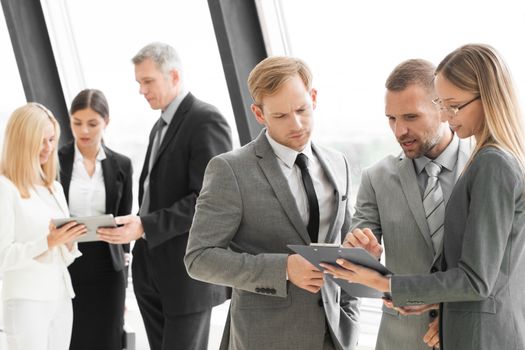 Three smart employees discussing documents using tablet pc at meeting