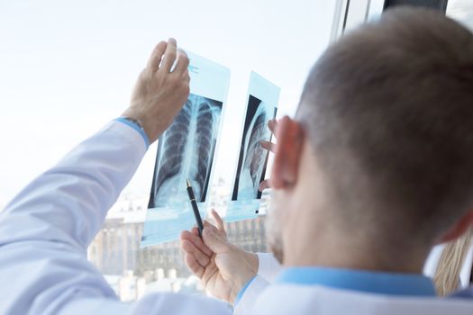 Two doctors examining a x-ray film by the window at clinical office