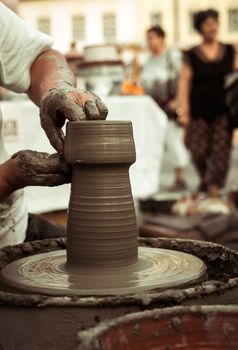 Sibiu City, Romania - 31 August 2019. Hands of a potter shaping a clay pot on a potter's wheel at the potters fair from Sibiu, Romania