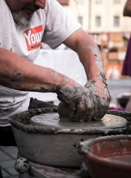 Sibiu City, Romania - 31 August 2019. Hands of a potter shaping a clay pot on a potter's wheel at the potters fair from Sibiu, Romania