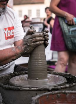 Sibiu City, Romania - 31 August 2019. Hands of a potter shaping a clay pot on a potter's wheel at the potters fair from Sibiu, Romania