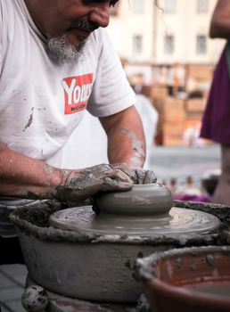 Sibiu City, Romania - 31 August 2019. Hands of a potter shaping a clay pot on a potter's wheel at the potters fair from Sibiu, Romania