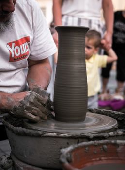 Sibiu City, Romania - 31 August 2019. Hands of a potter shaping a clay pot on a potter's wheel at the potters fair from Sibiu, Romania