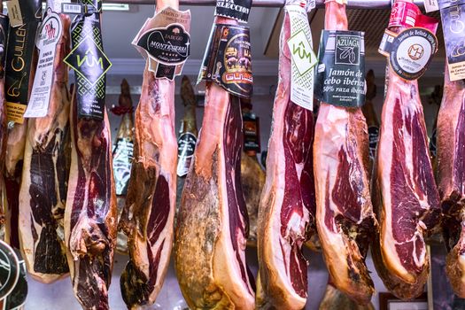 Malaga, Spain - May 24, 2018. Iberian ham (spanish prosciutto or jamon iberico) hanging at Ataranzanas Central Market, Malaga, Spain