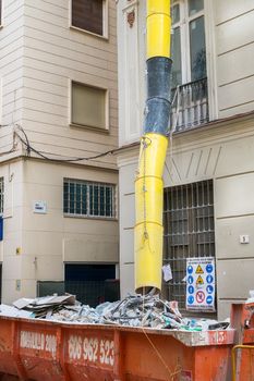 Malaga, Spain - March 23, 2018. Loaded dumpster near a building in renovation in Malaga city, Spain