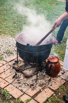 a country woman preparing a Romanian traditional food at the cauldron