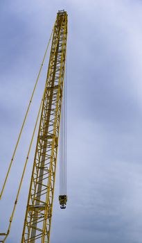 a large yellow crane with cloudy sky