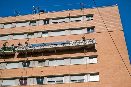 Malaga, Spain - February 23, 2018. Workers on the exterior scaffold elevator to repair the building