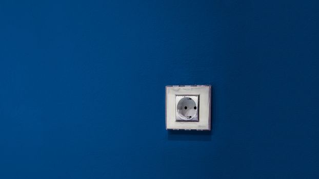 a white socket on the blue wall