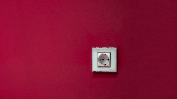 a white socket on the red wall