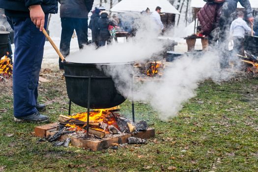 an unknown person prepares a traditional Romanian food prepared at the cauldron on the open fire, Christmas tradition