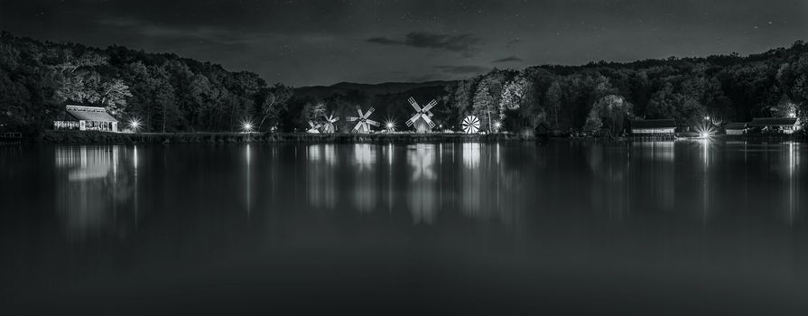 Landscape panorama with windmills at the blue hour in White Night of the Museums. Dumbrava lake, Astra Museum of Traditional Folk Civilization, Sibiu city, Romania