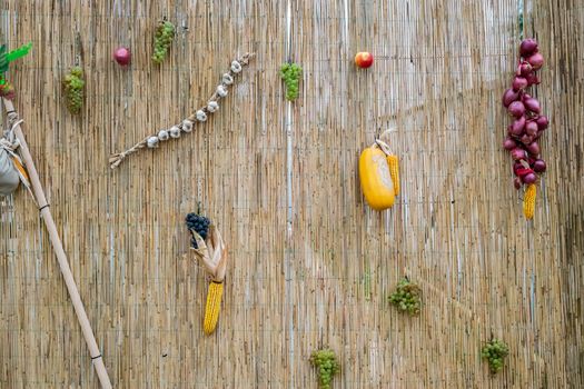 grapes, red onion, corn, garlic and pumpkin on a wicker wall