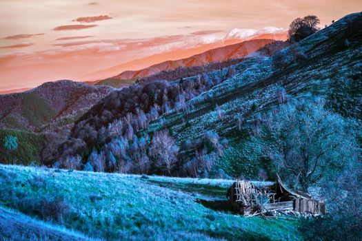 Autumn scene in infrared with old derelict wooden barn and Romanian Fagaras mountains in the back, Paltinis area, Sibiu county, Romania, 1400m.