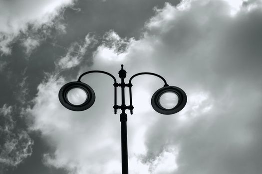 city lit light pole on day with cloudy sky