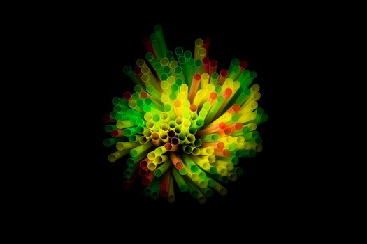 colored plastic drinking straws on black background