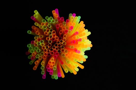 colored plastic drinking straws on black background