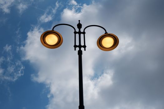 city lit light pole on day with cloudy sky