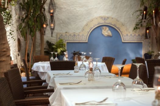 empty tables arranged with tableware, plates and glasses at the Spanish restaurant in Marbella city, Costa del sol, Spain