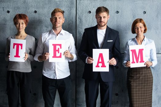 Business people holding TEAM letters printed on paper