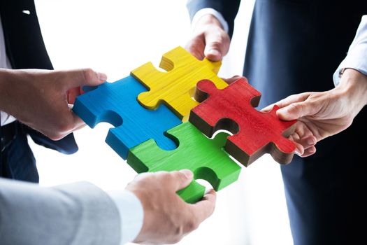 Business people team assembling four color jigsaw puzzle pieces unity cooperation ideas concept